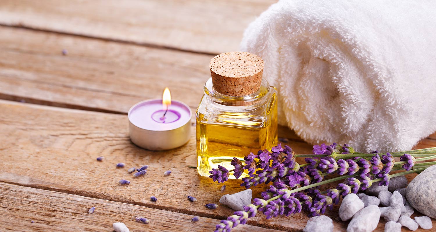 Holzboden mit Massageöl-Flasche, Lavendel, Handtuch und Kerze