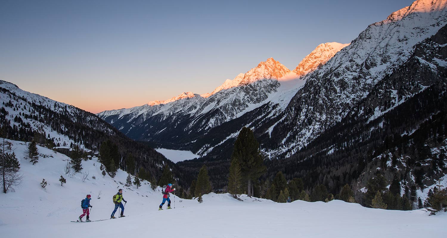Gruppo di sciatori fuori pista al tramonto in paesaggio innevato
