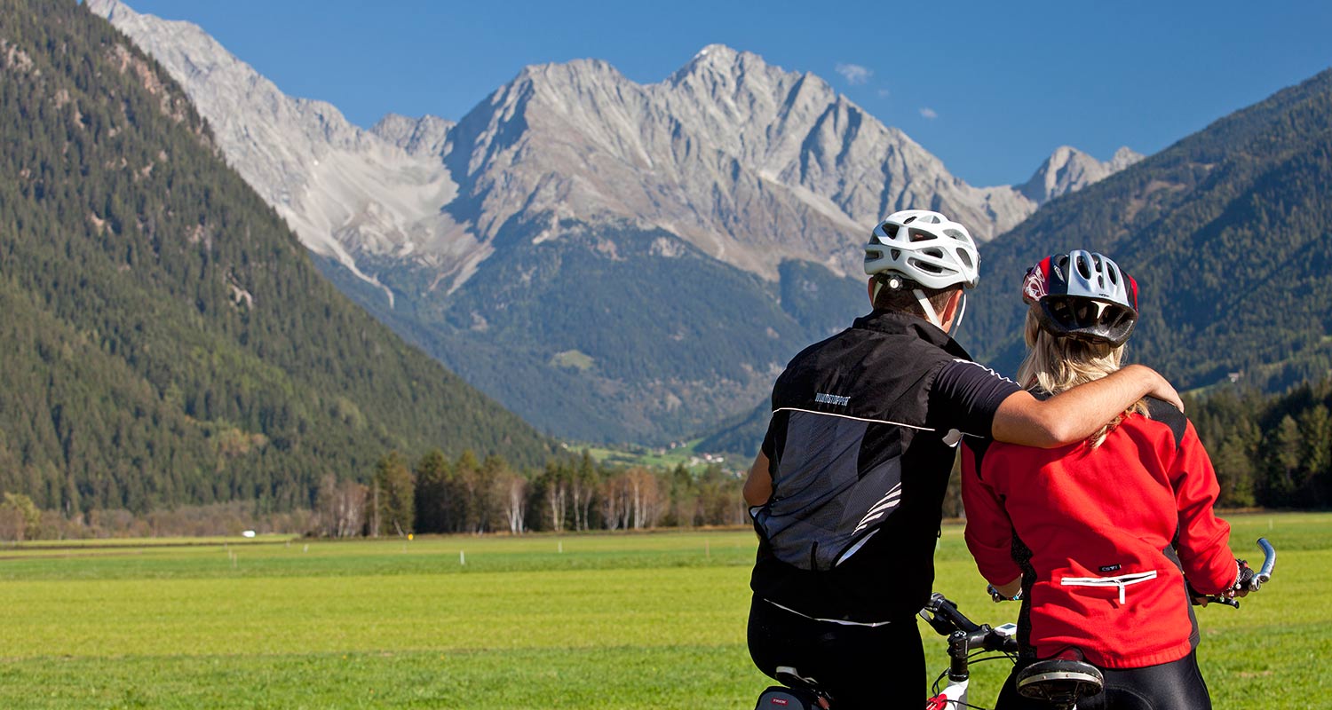 Radfahrer erholen sich bei einer kurzen Pause vor einem grünen Bergpanorama