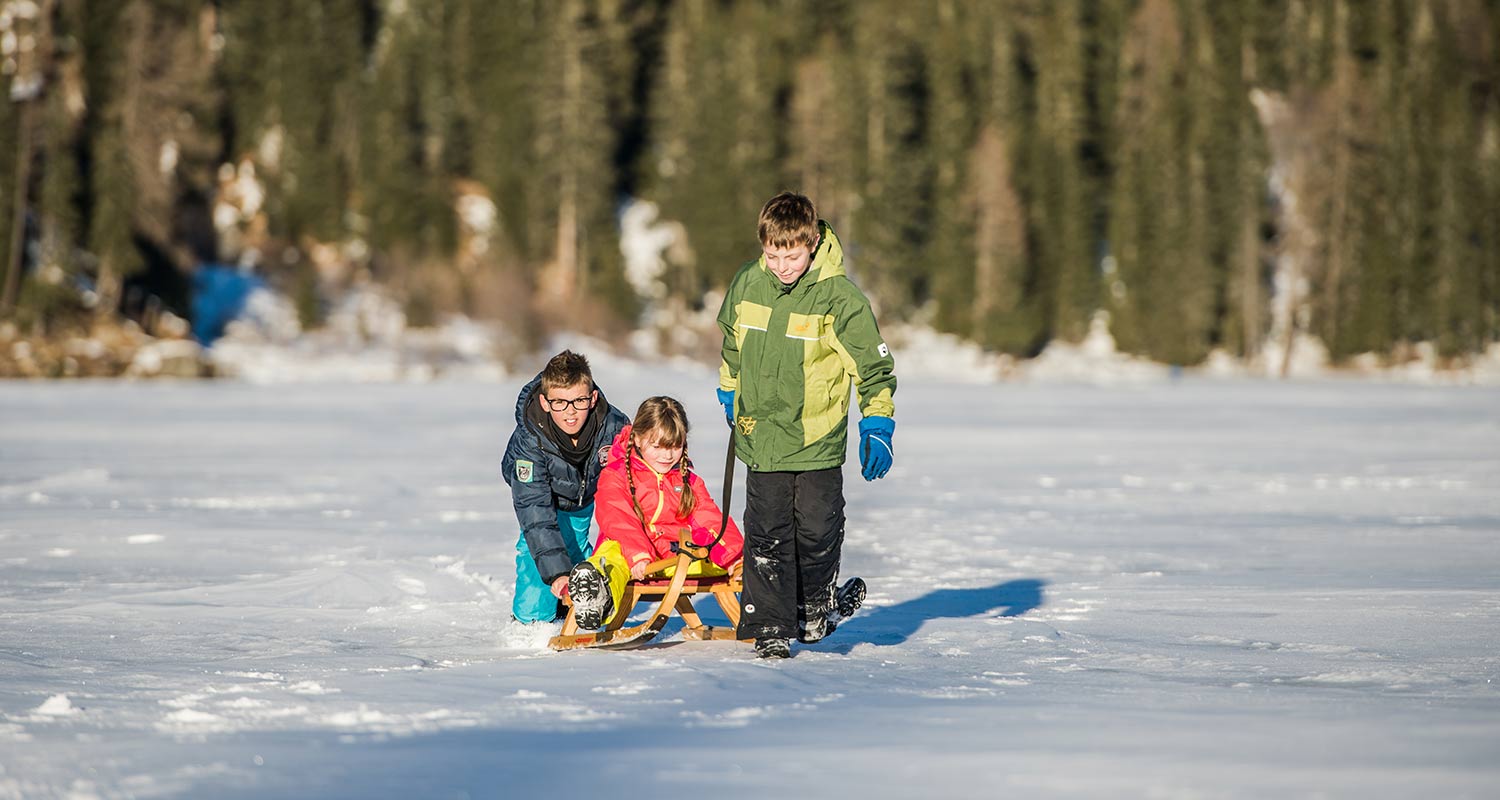 Children playing with toboggans on snowy surface