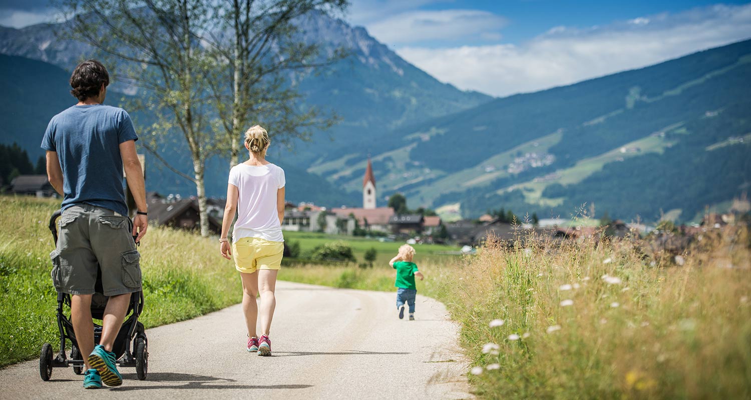 Famiglia con bambino piccolo passeggia per il villaggio di Rasen