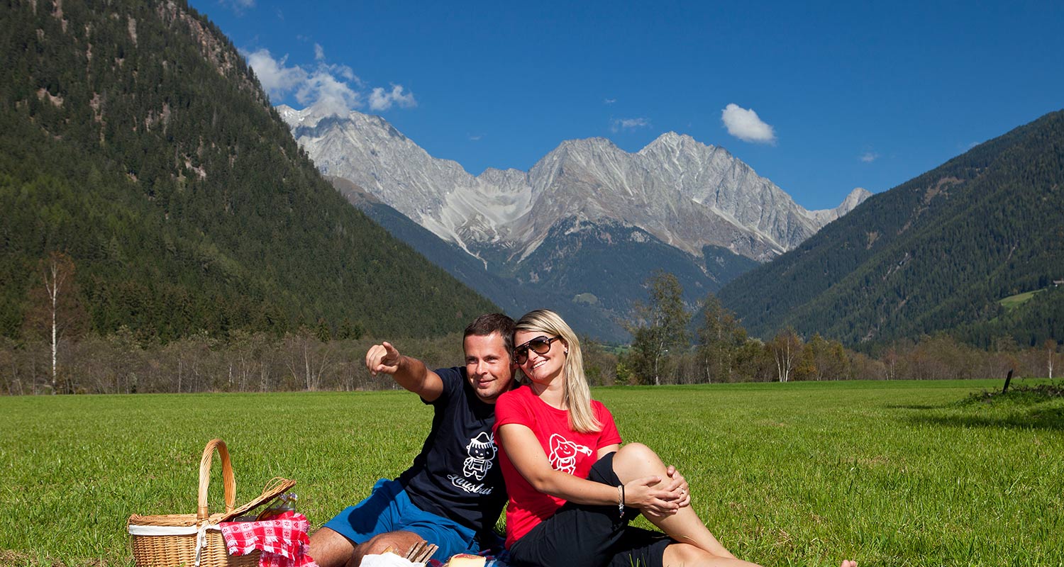 Coppia fa un picknick su un prato di montagna in una bella giornata estiva