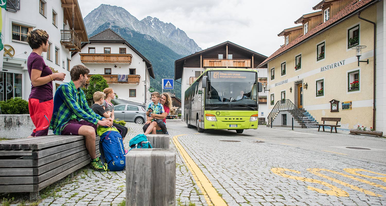 Personen warten an der Haltestelle in Rasen im Antholzertal auf den Linienbus