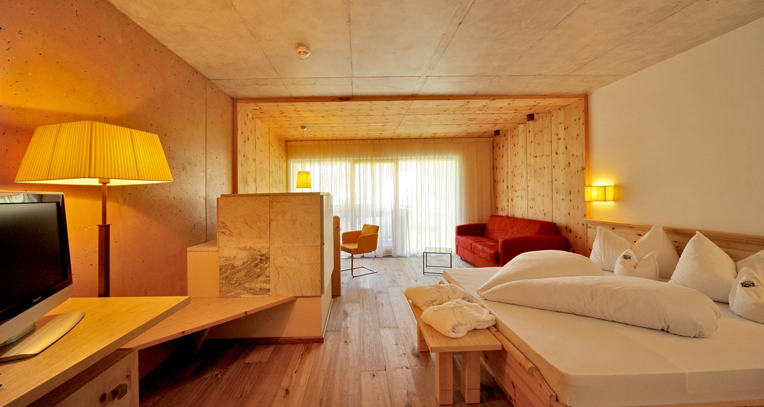 Ganz in Holz eingerichtetes Zimmer mit Doppelbett und Balkon des Sporthotel Rasen