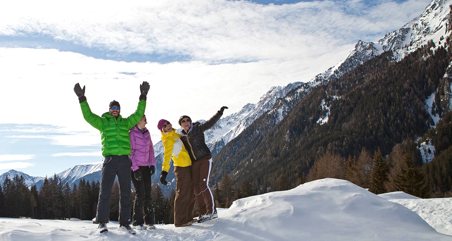 Gruppe von Personen scherzen in winterlicher Landschaft im Pustertal