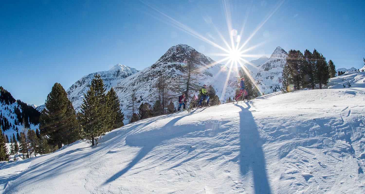 Skitourenläufer gehen einen schneebedeckten Hügel hoch an einem sonnigen Wintertag